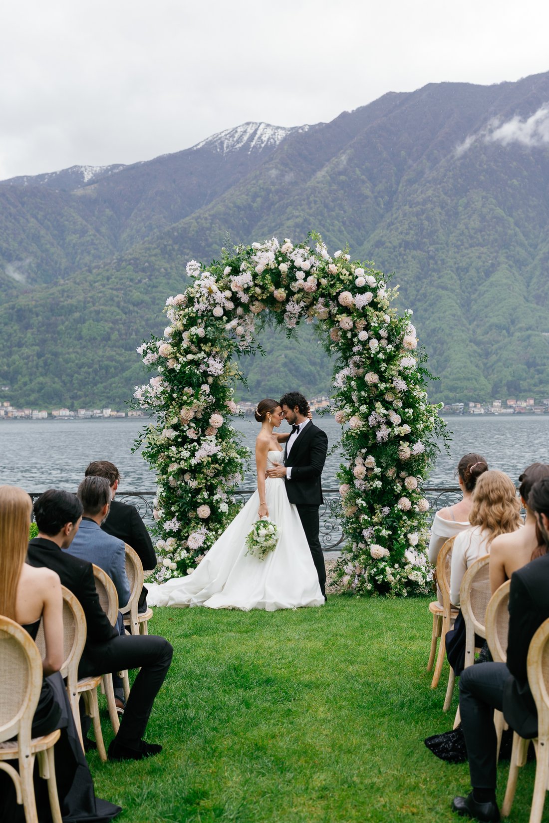Couple facing each other under a floral arch during their custom ceremony